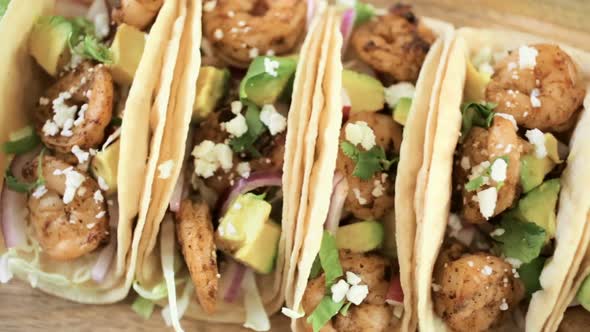 Close up of fresh chipotle shrimp tacos with cotija cheese on a white corn tortillas. alt