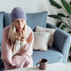 Unhappy Young woman wearing woolen hat and warm clothing at home and feeling cold. Energy crisis in - PhotoDune Item for Sale