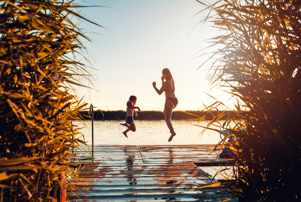 Single mother with her son enjoying on vacation jumping in lake from ...