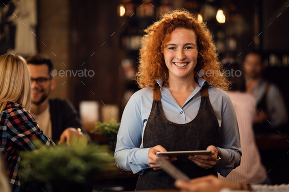Portrait of happy waitress with digital tablet in a pub.