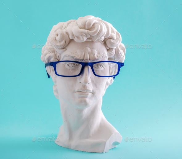 Plaster statue head wearing blue glasses on blue background. - Stock Photo - Images