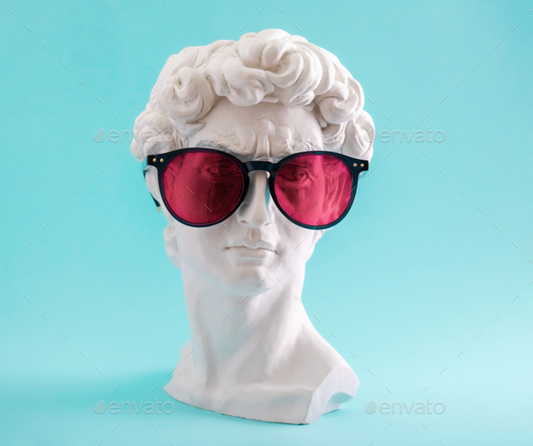 Plaster statue head wearing pink sunglasses on blue background. - Stock Photo - Images