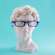 Plaster statue head wearing blue glasses on blue background. - PhotoDune Item for Sale