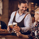 Happy waiter serving beer to female customer in a bar. - PhotoDune Item for Sale