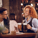 Young happy waitress serving beer to her customer in a bar. - PhotoDune Item for Sale