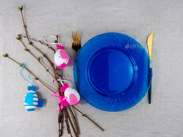 Easter table setting empty blue glass plate fork knife branches linen cloth Festive menu dish place