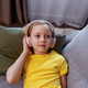Happy child listens to music or audiobook at home on couch. Little school kid wearing headphones - PhotoDune Item for Sale