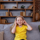 Happy child listens to music or audiobook at home on couch. Little school kid wearing headphones. - PhotoDune Item for Sale