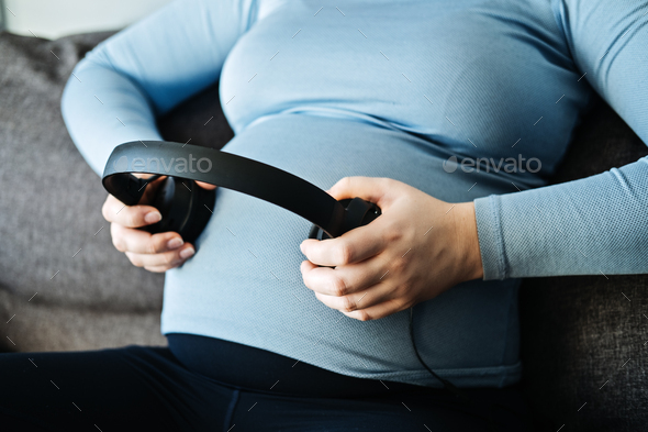 Pregnancy music for the unborn baby. Brain development. Pregnant woman with headphones on her belly - Stock Photo - Images