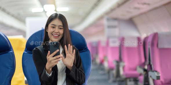 Young woman sitting with phone video call on the aircraft seat near the window during the flight in - Stock Photo - Images