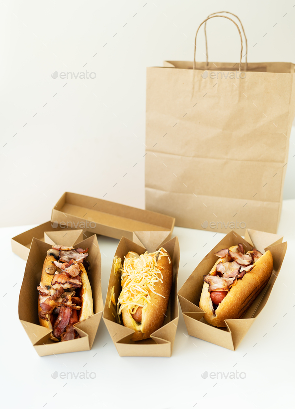 Food delivery concept. Different types of hot dogs in craft packaging on the table, vegan, meat