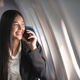 Traveling and technology. Flying at first class. Pretty young business woman using smartphone while - PhotoDune Item for Sale