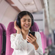 Cheerful female passenger in headphones for noise cancellation watching online movie during - PhotoDune Item for Sale