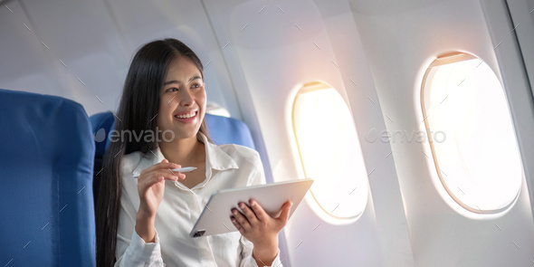 Beautiful asian travel woman watching movie on digital tablet in airplane - Stock Photo - Images