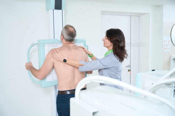 Female radiologist taking X-ray of man in clinic - Stock Photo - Images