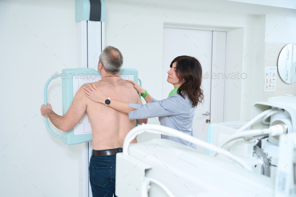 Adult man standing in a medical gown undergoing a chest x-ray procedure - Stock Photo - Images