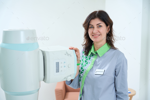 Happy female doctor standing beside hospital medical scanner - Stock Photo - Images