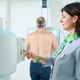 Doctor operating X-ray machine while standing near the patient - PhotoDune Item for Sale