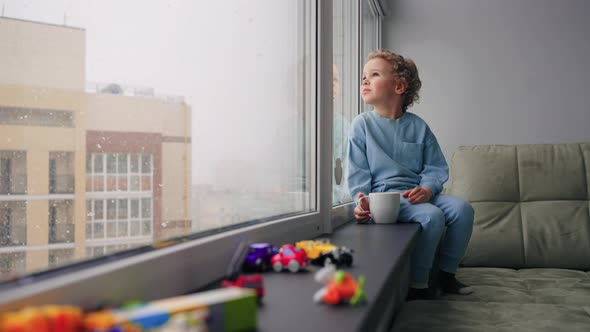 Cute Little Boy is Sitting Alone in Children Room with Many of Toys Cozy Home Atmosphere in Winter alt