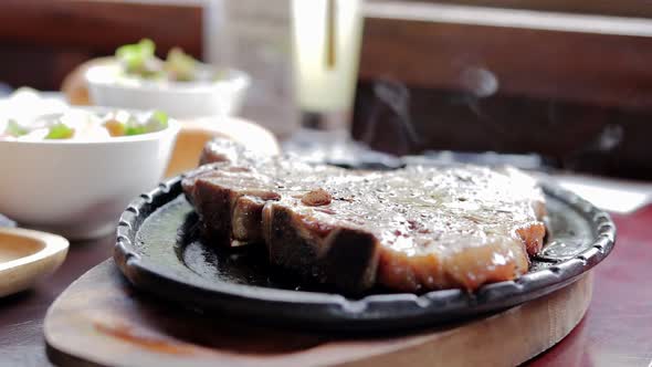 Grilled beef steak sizzling in a hot black cast iron pan alt