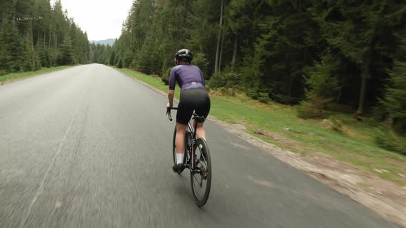 Cyclist riding bicycle out of saddle. Woman cycling on bike. Athlete training on bike alt