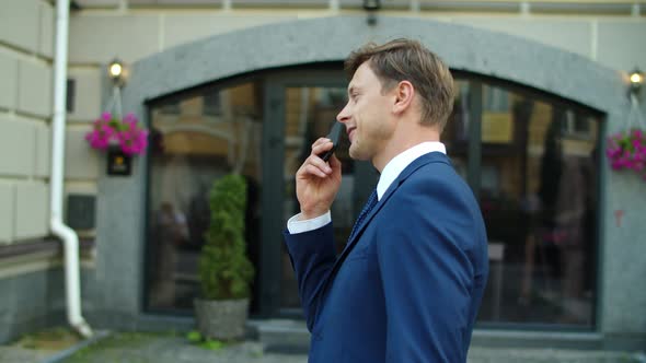 Cheerful Business Man Recording Voice Messages on Smartphone Outside alt