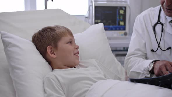 Doctor Speaking with Little Boy about X-Ray Results alt