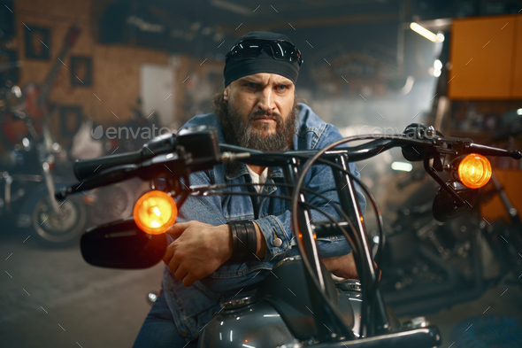 Handsome bearded man testing new motorbike in garage store - Stock Photo - Images