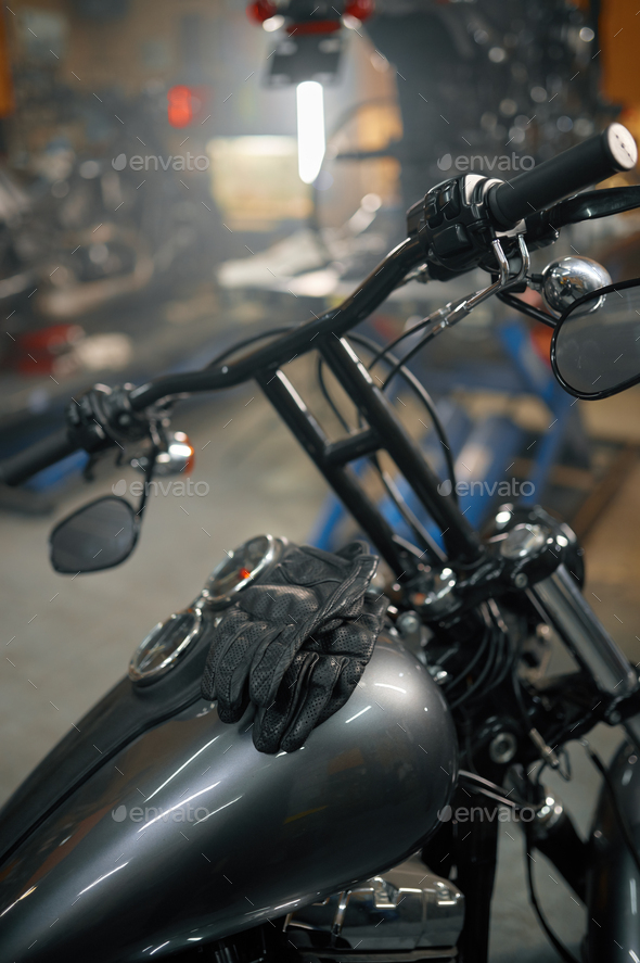 Motorcycle garage, closeup view on leather biker gloves on motorbike gas tank - Stock Photo - Images