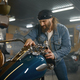Mature male biker examining his new motorbike standing with garage - PhotoDune Item for Sale