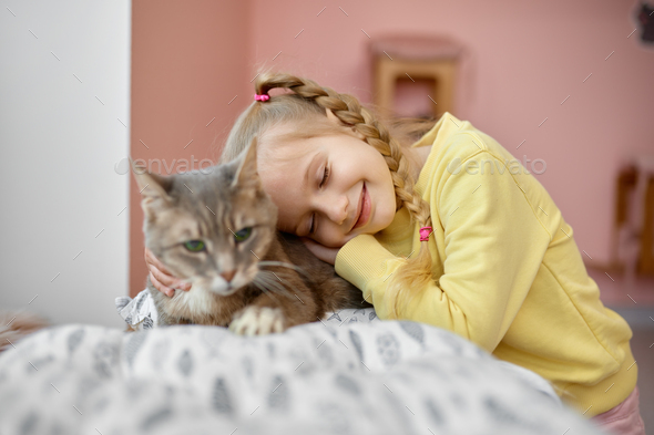 Happy smiling girl petting fluffy cat having fun time in animal shelter - Stock Photo - Images