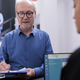 Elderly patient standing at hospital reception signing medical insurance paper - PhotoDune Item for Sale