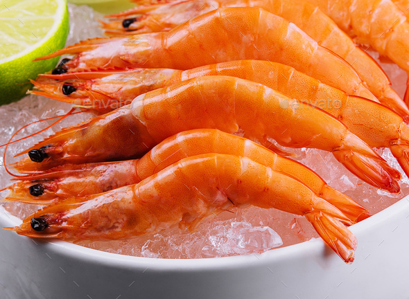 A group of tiger shrimp on a bowl of ice with lime