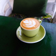 Green cup of cappuccino with latte art on dark green wooden table. - PhotoDune Item for Sale