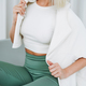 Close up portrait of young blonde woman in sportswear sitting on background of white wall - PhotoDune Item for Sale