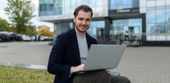 young charismatic successful businessman working on laptop outside - Stock Photo - Images