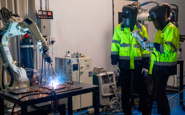 Two engineer or technician worker men with face mask protection of light stand in front of welding
