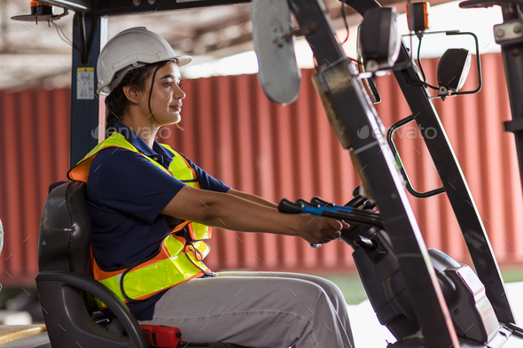 Indian woman staff worker work forklift driver at port cargo warehouse container
