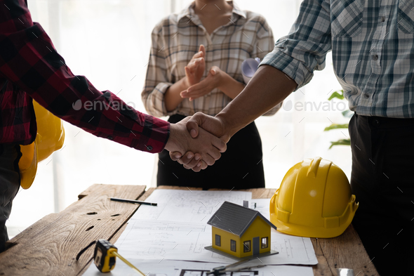 Architect and engineer construction workers shaking hands while working for teamwork. - Stock Photo - Images