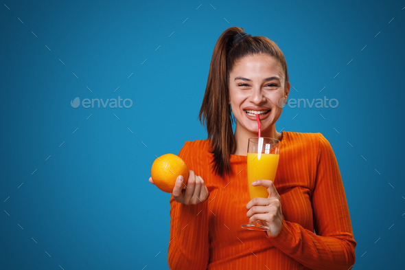Young Woman Drinks Orange Juice And Holding Orange In His Hand In A