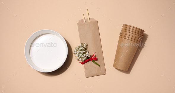 Empty paper plate for soup and brown cardboard cups on beige background, top view