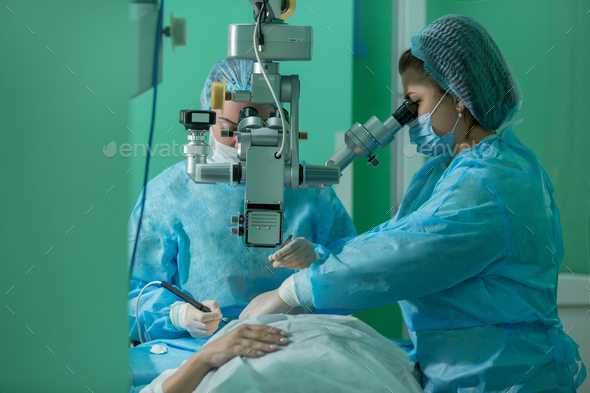 a young woman ophthalmologist performs an operation on the patient\'s eye