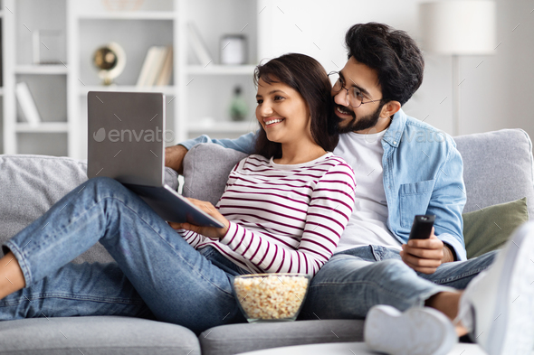 Relaxed multicultural spouses chilling on couch at home