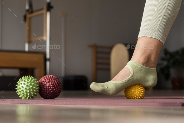Trainer doing leg stretching exercises with fitness rubber balls. Fitness trainer doing exercises in
