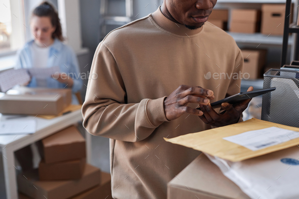 Close-up of young black man checking data in tablet in post office