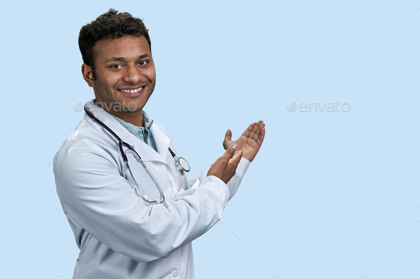Portrait of male indian doctor showing copy space. - Stock Photo - Images
