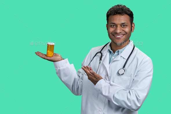 Portrait of male indian doctor holding orange medicine bottle. - Stock Photo - Images