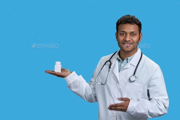 Portrait of male indian doctor holding white medicine bottle. - Stock Photo - Images