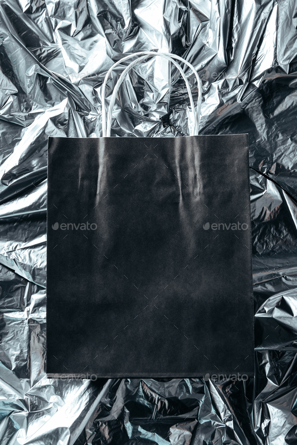 top view of blank paper bag on silver wrapping paper background, black friday concept