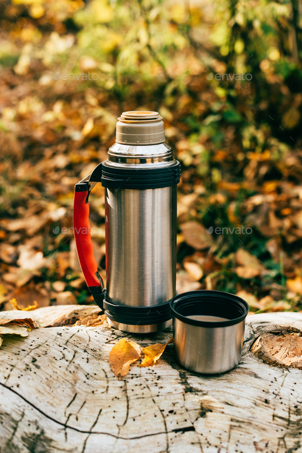 metallic camping thermos on beautiful autumnal background Stock